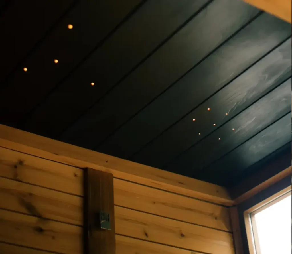 A close-up of the black-clad ceiling in a Modern Mod Pod Sauna with little light holes shining in various patterns.