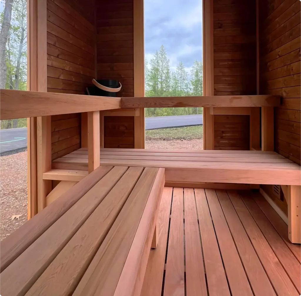 The inside of a Mod Pod Sauna showing the two-tiered, L-shaped, Social bench and full-height windows.