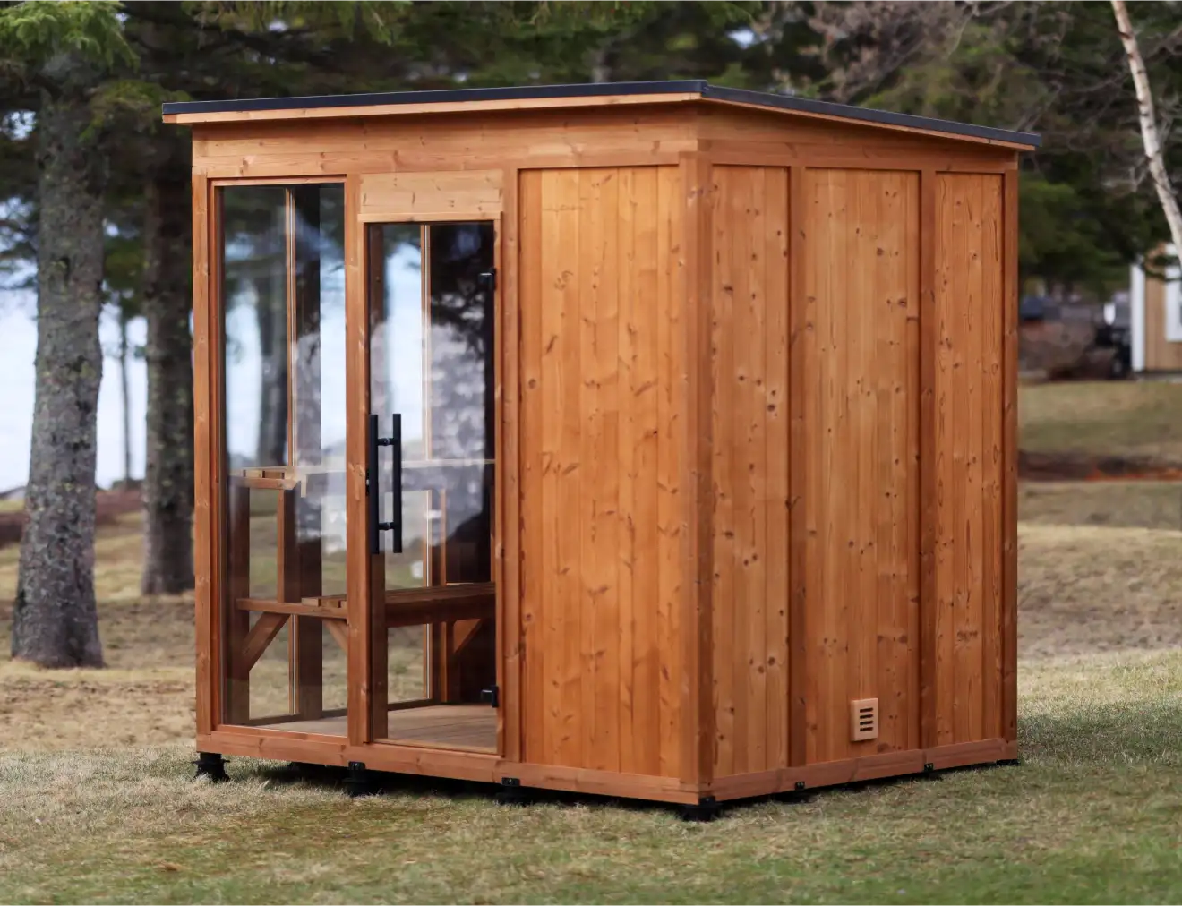 A side view of the Traditional Mod Pod sauna with a mono-pitch roof, Kodiak cladding, Clear Pine posts and a full-height window next to the glass door